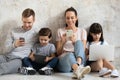 Happy technology addicted parents and kids use devices at home Royalty Free Stock Photo