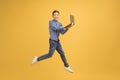 Happy teen boy with laptop computer jumping up over yellow background Royalty Free Stock Photo