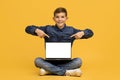 Happy Teen Boy Sitting On Floor And Pointing At Blank Laptop Screen Royalty Free Stock Photo