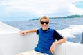 Happy teen boy in sunglasses on the yacht. Tropical sea in the b