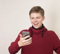 Teen boy watching media content in a smart phone or reading text message on mobile phone and laughing Royalty Free Stock Photo