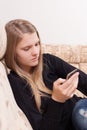 Happy teen with cellphone sitting on the sofa in the living room