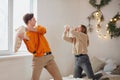 Happy teen couple having fun fighting with pillows on bed in New Years festively decorated bedroom Royalty Free Stock Photo