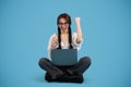 Happy teen european girl student with pigtails in glasses with laptop, rejoices to victory, make success gesture