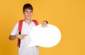 Happy teen european schoolboy with backpack points finger at abstract cloud for words and thoughts