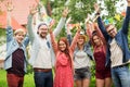 Happy teen friends waving hands at summer garden