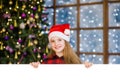 Happy teen girl in christmas hat peeking above white banner Royalty Free Stock Photo