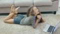 Happy teen girl on a couch uses laptop. Steadicam shot