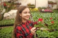 happy teen girl florist planting pot plants in greenhouse, spring