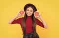 happy teen girl in hat with grapefruit. vitamin and dieting. child eating healthy food.