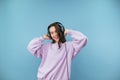 Happy teen girl in headphones with a smile on her face dances on a blue background, looks at the camera and laughs Royalty Free Stock Photo