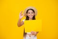 happy teen girl hold empty advertisement paper with copy space on yellow background. ok