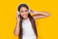 happy teen girl listening music in headphones on yellow background Royalty Free Stock Photo