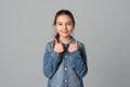 happy teen girl looking at camera and showing thumbs up, isolated on grey background, wearing in denim jacket Royalty Free Stock Photo