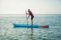 Happy teen girl paddling on sup board in Baltic sea