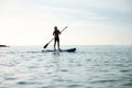 Happy teen girl paddling on sup board in Baltic sea