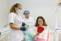 Happy teen girl patient looking in the mirror at the teeth, sitting in the dental chair Royalty Free Stock Photo