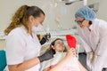 Happy teen girl patient looking in the mirror at the teeth, sitting in the dental chair Royalty Free Stock Photo