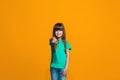 The happy teen girl pointing to you, half length closeup portrait on orange background. Royalty Free Stock Photo