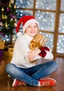 Happy teen girl in red christmas hat hugging christmas gift box Royalty Free Stock Photo