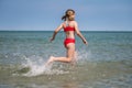 Happy teen girl running and splashing water in turquoise sea at summer holidays Royalty Free Stock Photo