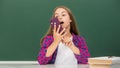 happy teen girl talking on mobile phone in high school at blackboard, voice email Royalty Free Stock Photo