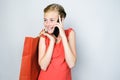 Happy teen girl talking on smartphone and holding paper shopping bag in her hand. Royalty Free Stock Photo