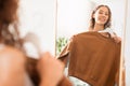 Happy teen girl trying on sweatshirt looking in mirror indoors Royalty Free Stock Photo