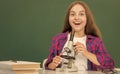 happy teen girl using microscope in high school at blackboard, chemistry Royalty Free Stock Photo