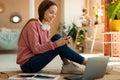 Happy teen girl using smartphone and laptop for online learning, messaging on phone with his fellow students or tutor