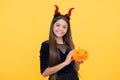 Happy teen girl wear devil horns costume holding pumpkin to create jack o lantern on halloween party, creepy halloween Royalty Free Stock Photo