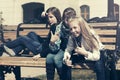 Happy teen girls sitting on bench in city street Royalty Free Stock Photo