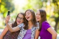 Happy teen girls taking selfie in park