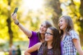 Happy teen girls taking selfie in park