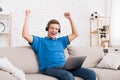 Happy teen guy celebrating victory on laptop