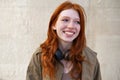 Happy teen redhead girl laughing standing on urban wall background. Royalty Free Stock Photo