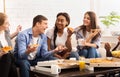 Happy teen roommates eating pizza and chatting at home