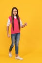 happy teen school girl walking on yellow background, copy space, fashion Royalty Free Stock Photo