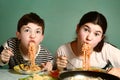 Happy teen siblings boy and girl eat spaghetti