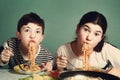 Happy teen siblings boy and girl eat spaghetti