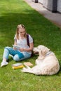 happy teen student girl using tablet while sitting on grass