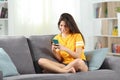 Happy teen using a mobile phone on a couch