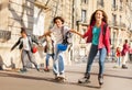 Boys and girls rollerblading holding hands at city