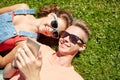 Happy teenage couple smartphone lying on grass