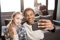 Happy teenage couple taking selfie with friends standing behind Royalty Free Stock Photo