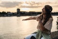 Happy teenage female tourist sitting on sea promenade of an old city in sunset. Young woman world traveler singing her favorite Royalty Free Stock Photo