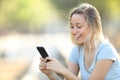 Happy teenage girl checking phone content in a park