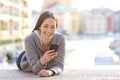 Happy teenage girl checking phone outdoors