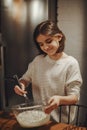 Happy teenage girl cooking in kitchen, whisking eggs and milk in bowl while preparing dough Royalty Free Stock Photo