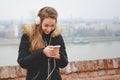 Happy teenage girl with headphones and phone enjoys listening to the music and smiles